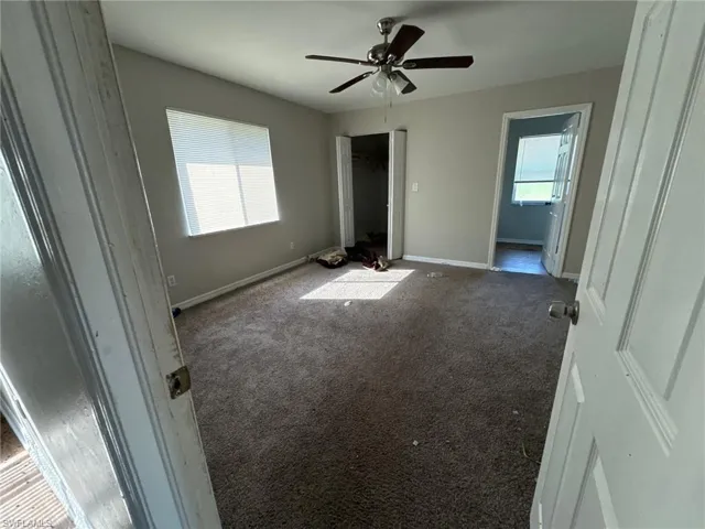 Unfurnished bedroom featuring ceiling fan and dark carpet