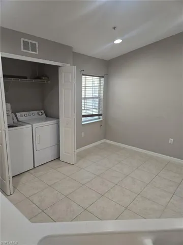 Washroom featuring washing machine and dryer, light tile patterned flooring, and recessed lighting