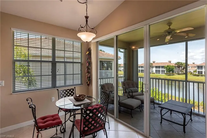 Tiled dining area featuring vaulted ceiling, healthy amount of natural light, a water view, and a ceiling fan