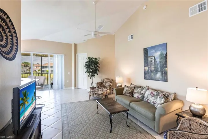 Living area with tile patterned floors, high vaulted ceiling, and a ceiling fan