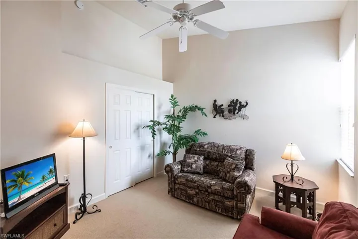 Carpeted living area featuring a ceiling fan and baseboards