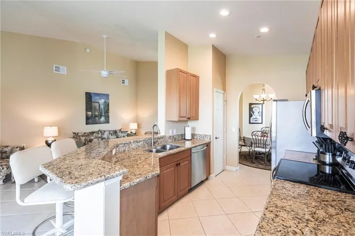 Kitchen featuring open floor plan, light stone countertops, arched walkways, a peninsula, and a breakfast bar area