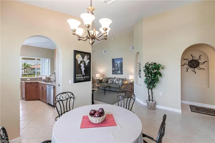 Dining area featuring arched walkways, light tile patterned floors, and a chandelier