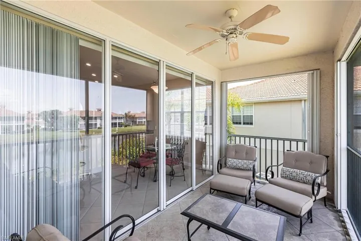 Sunroom / solarium featuring a ceiling fan, a water view, a balcony, and a residential view