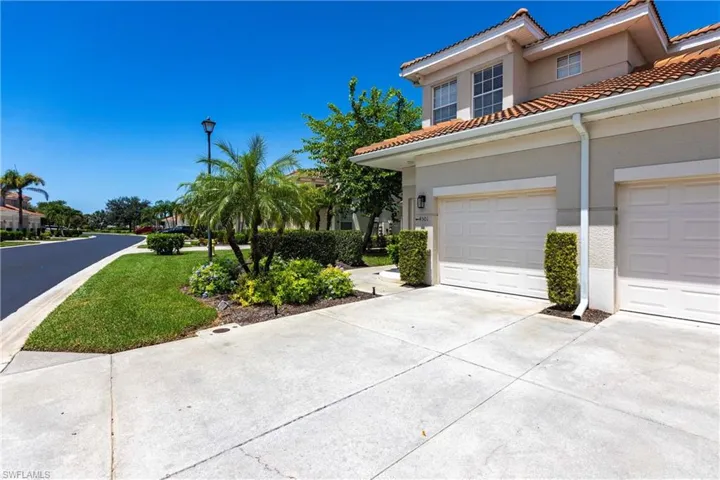 Mediterranean / spanish house with a garage, driveway, stucco siding, a tiled roof, and a front lawn