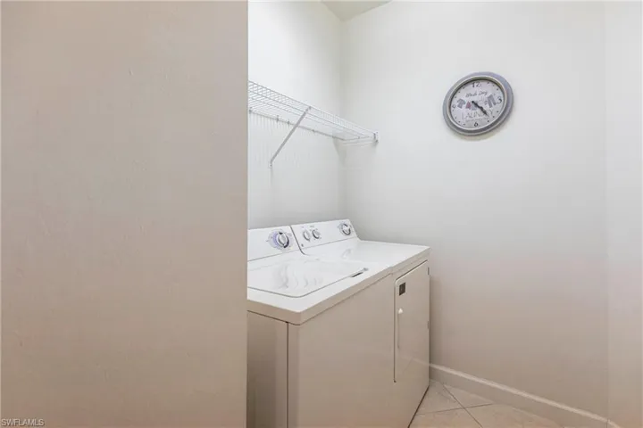 Laundry area featuring light tile patterned floors and washer and clothes dryer