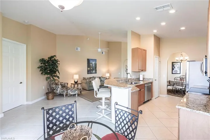 Kitchen featuring light stone counters, a peninsula, light tile patterned floors, arched walkways, and recessed lighting