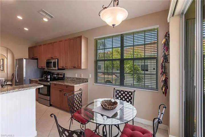 Kitchen featuring light stone countertops, appliances with stainless steel finishes, light tile patterned flooring, recessed lighting, and brown cabinets