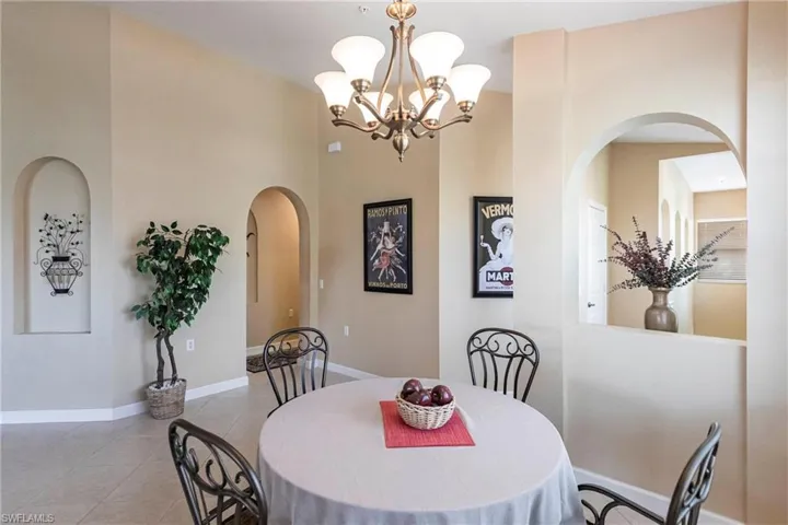 Tiled dining space featuring arched walkways and a chandelier