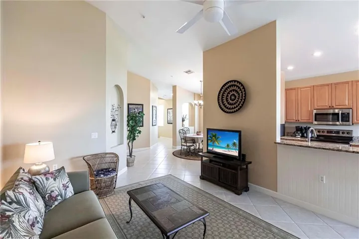 Living area with light tile patterned floors, a ceiling fan, recessed lighting, arched walkways, and a chandelier