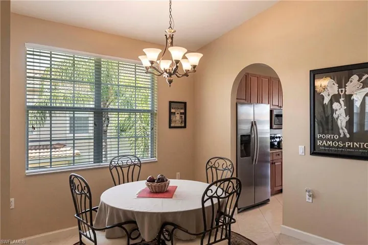 Dining room with light tile patterned flooring, arched walkways, and a chandelier