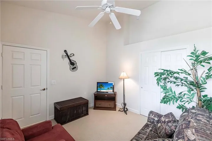 Carpeted living area with baseboards and ceiling fan