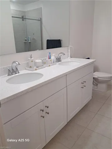 Master bathroom with walk in shower, vanity, toilet, and tile patterned flooring