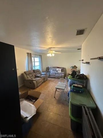 Living area featuring a textured ceiling, a ceiling fan, and dark tile patterned flooring