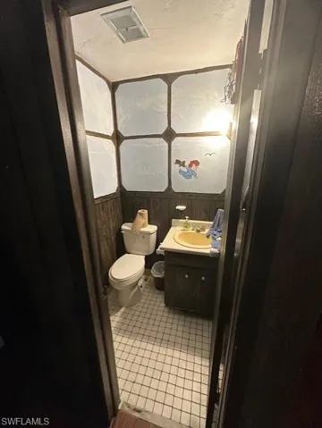 Half bath with vanity, wooden walls, and wainscoting