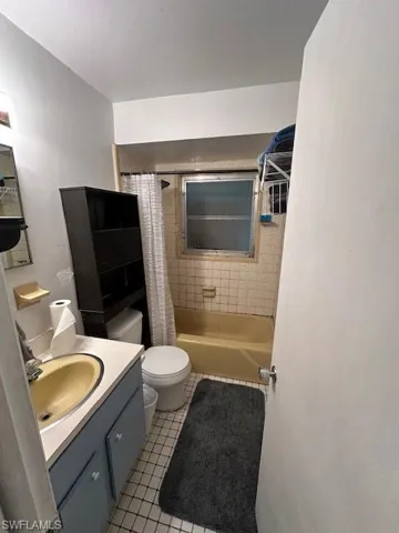 Full bath with vanity, shower / tub combo, and tile patterned flooring