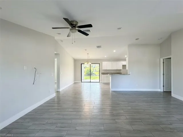 Unfurnished living room featuring ceiling fan, vaulted ceiling, wood tiled floors, and suspended lighting