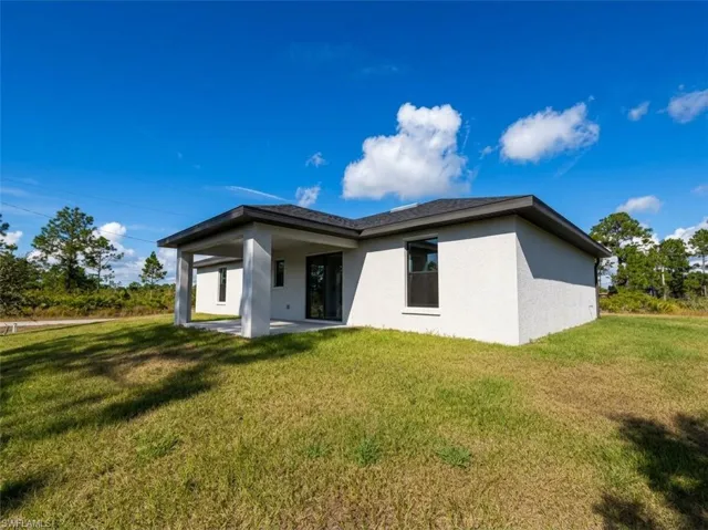 Back of house with a lawn, stucco siding, and a patio