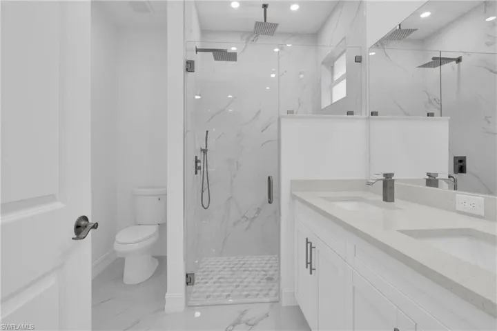 Full bathroom featuring light marble finish floors, double vanity, a marble finish shower, and recessed lighting