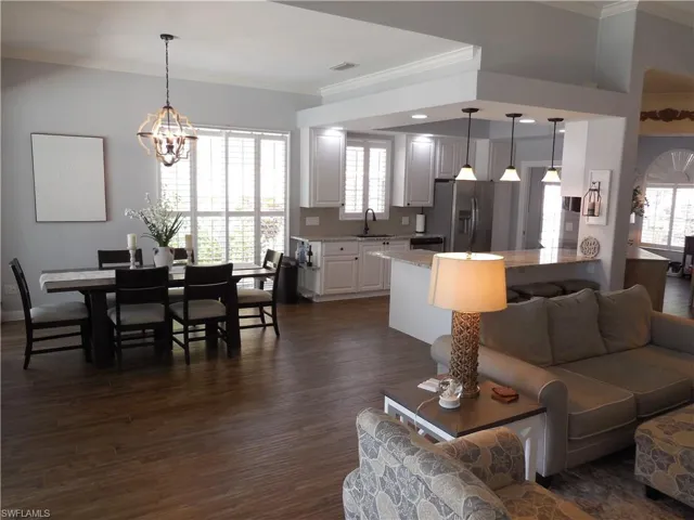 Living area featuring a notable chandelier, visible vents, ornamental molding, and dark wood-style flooring