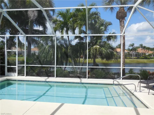 Outdoor pool featuring glass enclosure, a water view, and a patio