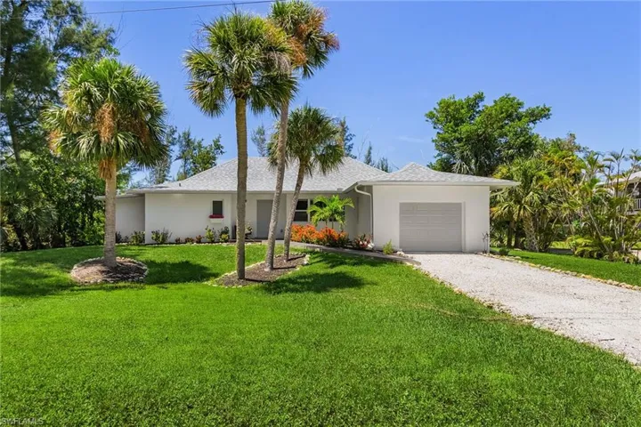 Ranch-style house featuring gravel driveway, a garage, a front yard, and stucco siding