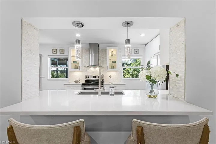 Kitchen featuring white cabinetry, a kitchen breakfast bar, decorative backsplash, and recessed lighting