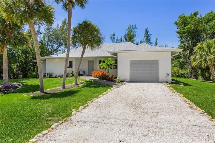 Ranch-style house with gravel driveway, a front yard, a garage, and stucco siding