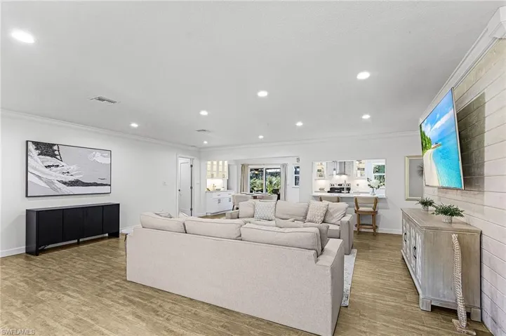 Living room with ornamental molding, light wood finished floors, and recessed lighting