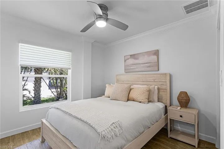 Bedroom with ornamental molding, wood finished floors, and a ceiling fan