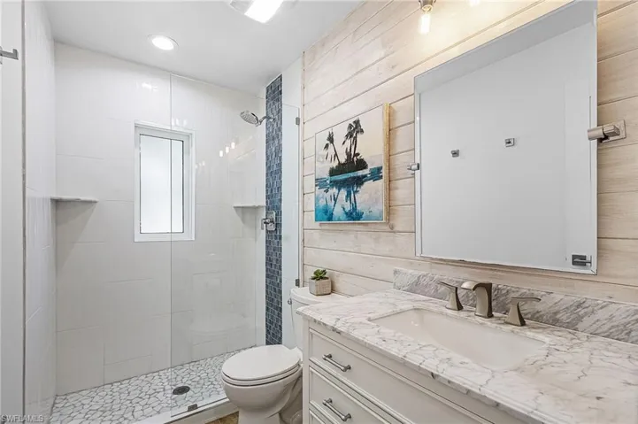 Full bath with vanity, a shower stall, and wooden walls