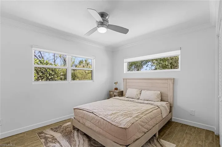 Bedroom with crown molding, wood finished floors, and ceiling fan