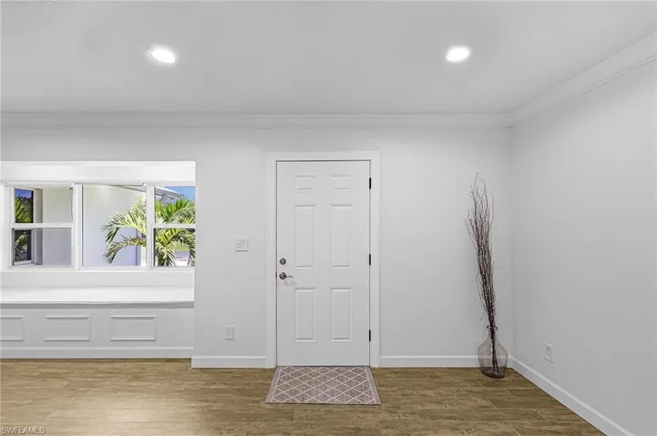 Foyer entrance featuring light wood-style flooring, crown molding, and recessed lighting