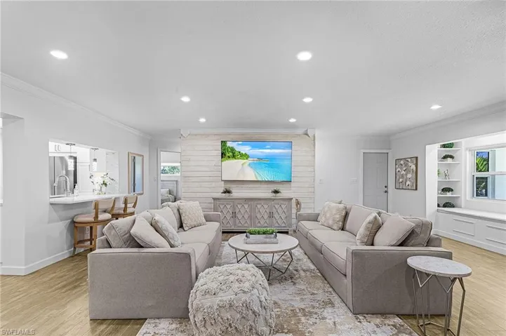 Living room featuring light wood-style flooring, ornamental molding, recessed lighting, and healthy amount of natural light