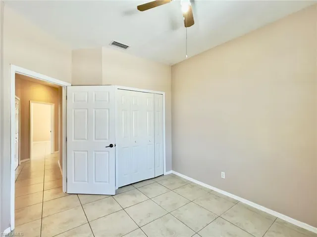 Unfurnished bedroom featuring a closet, a ceiling fan, and light tile patterned floors