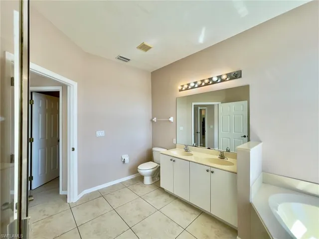 Bathroom featuring double vanity, a garden tub, and light tile patterned floors
