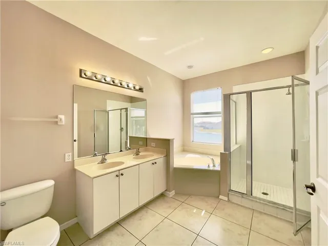 Full bathroom with double vanity, a stall shower, a bath, and light tile patterned floors