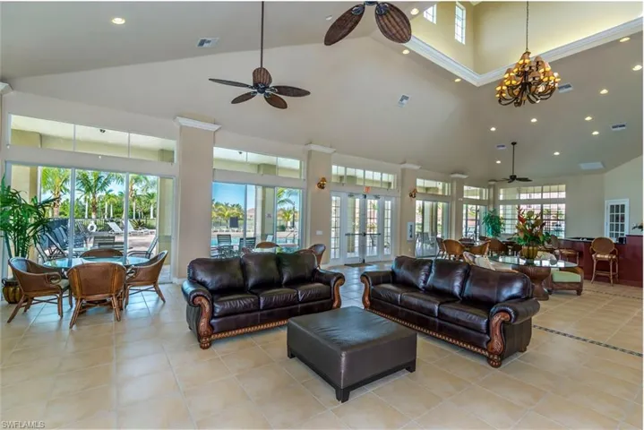 Living area featuring ceiling fan, recessed lighting, light tile patterned floors, and a high ceiling
