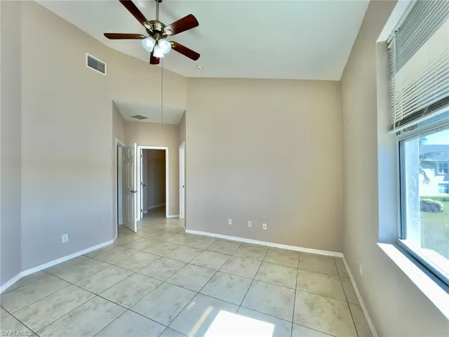 Unfurnished room featuring a ceiling fan, light tile patterned flooring, and lofted ceiling
