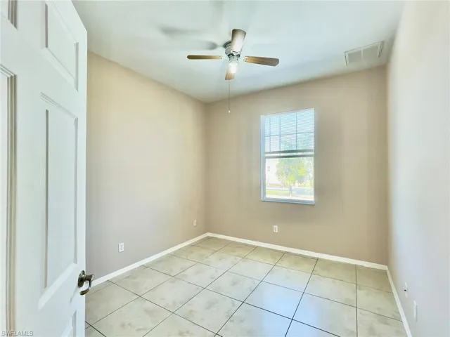 Empty room featuring ceiling fan and light tile patterned floors