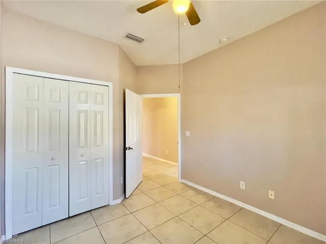 Unfurnished bedroom featuring a closet, ceiling fan, and light tile patterned flooring