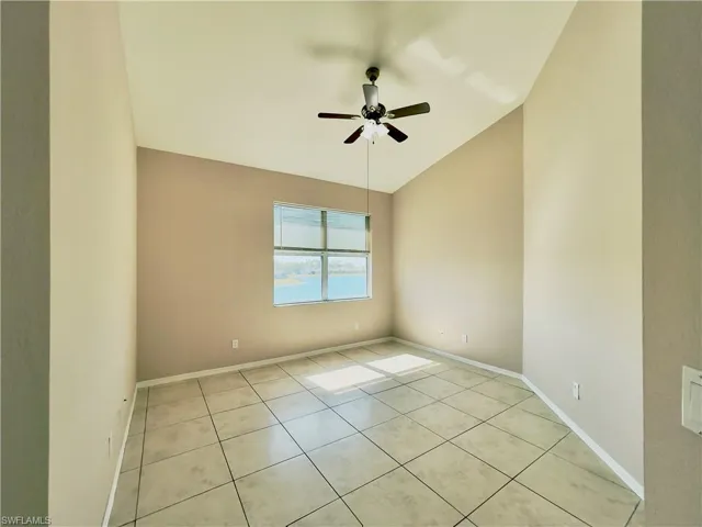 Unfurnished room with lofted ceiling, ceiling fan, and light tile patterned flooring