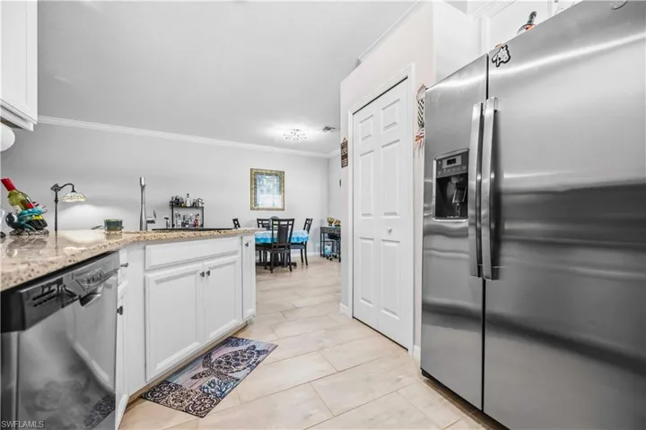 Kitchen featuring stainless steel appliances, crown molding, white cabinetry, light stone countertops, and a peninsula