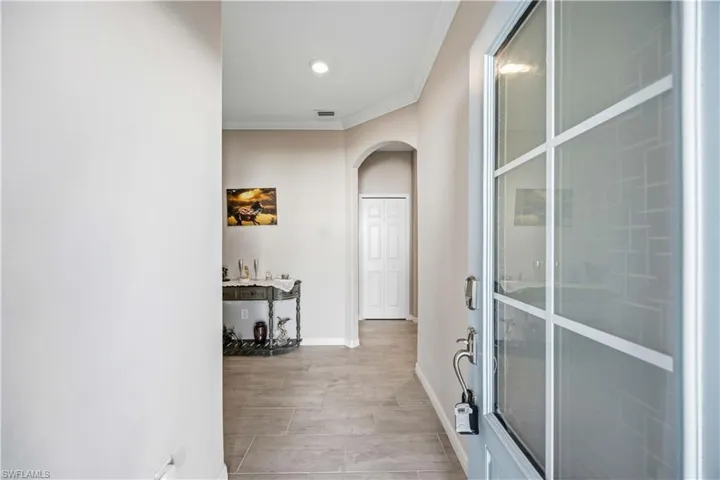 Hallway featuring ornamental molding, arched walkways, and wood finish floors