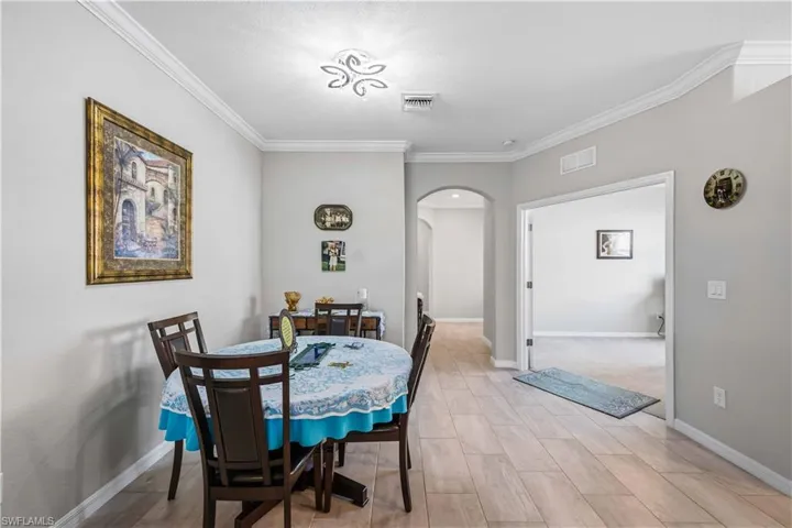 Dining area with arched walkways, ornamental molding, and wood finish floors
