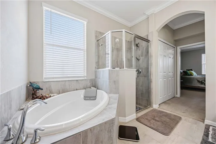 Full bath with a garden tub, a shower stall, ornamental molding, ensuite bath, and tile patterned floors