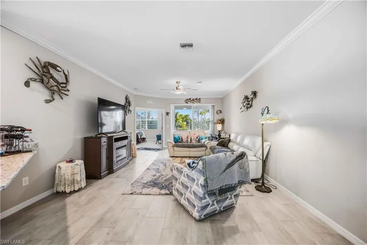Living room featuring ornamental molding, a ceiling fan, and wood tiled floors