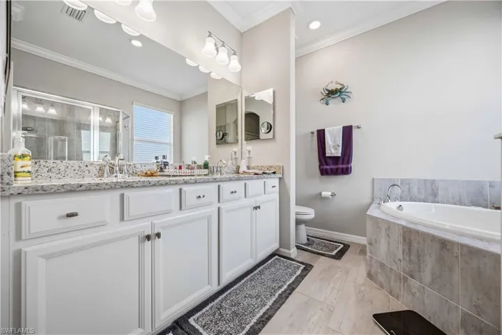 Bathroom with double vanity, a shower stall, a bath, ornamental molding, and recessed lighting