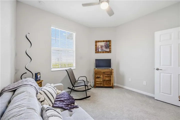 Living area with light colored carpet and a ceiling fan