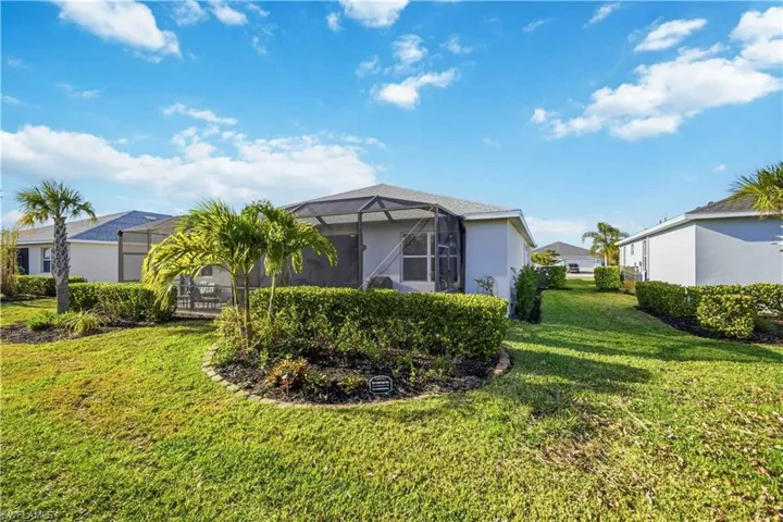 Rear view of house featuring glass enclosure, a sunroom, a yard, and stucco siding